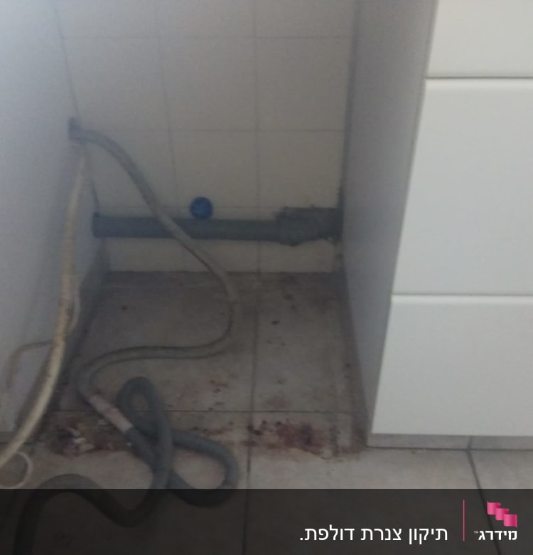 צינור מים מתחת לכיור עם לכלוך על הרצפה